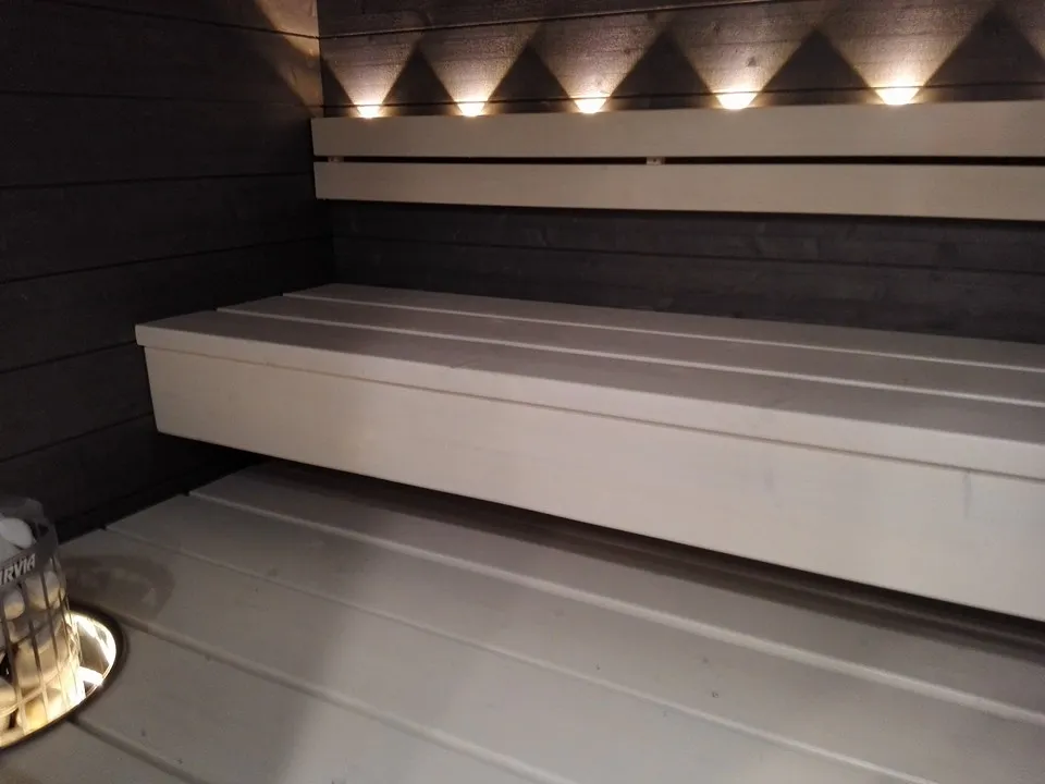 Saunan sisätilat, valkoiset penkit ja epäsuora valaistus.